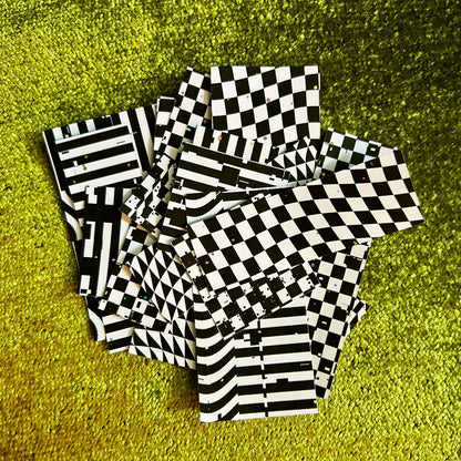 Black and white checkered and striped sticker pieces on a green textured surface