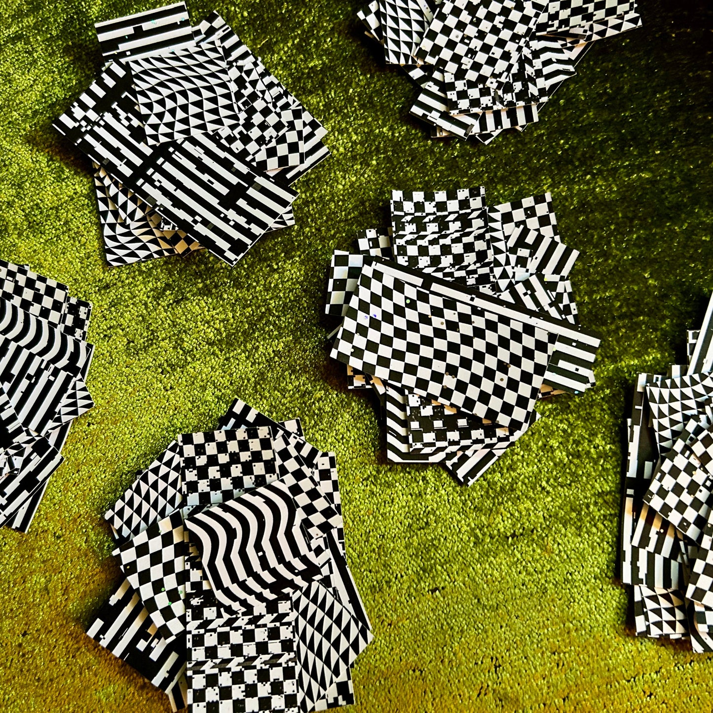 Black and white checkered sticker scraps on a textured green surface