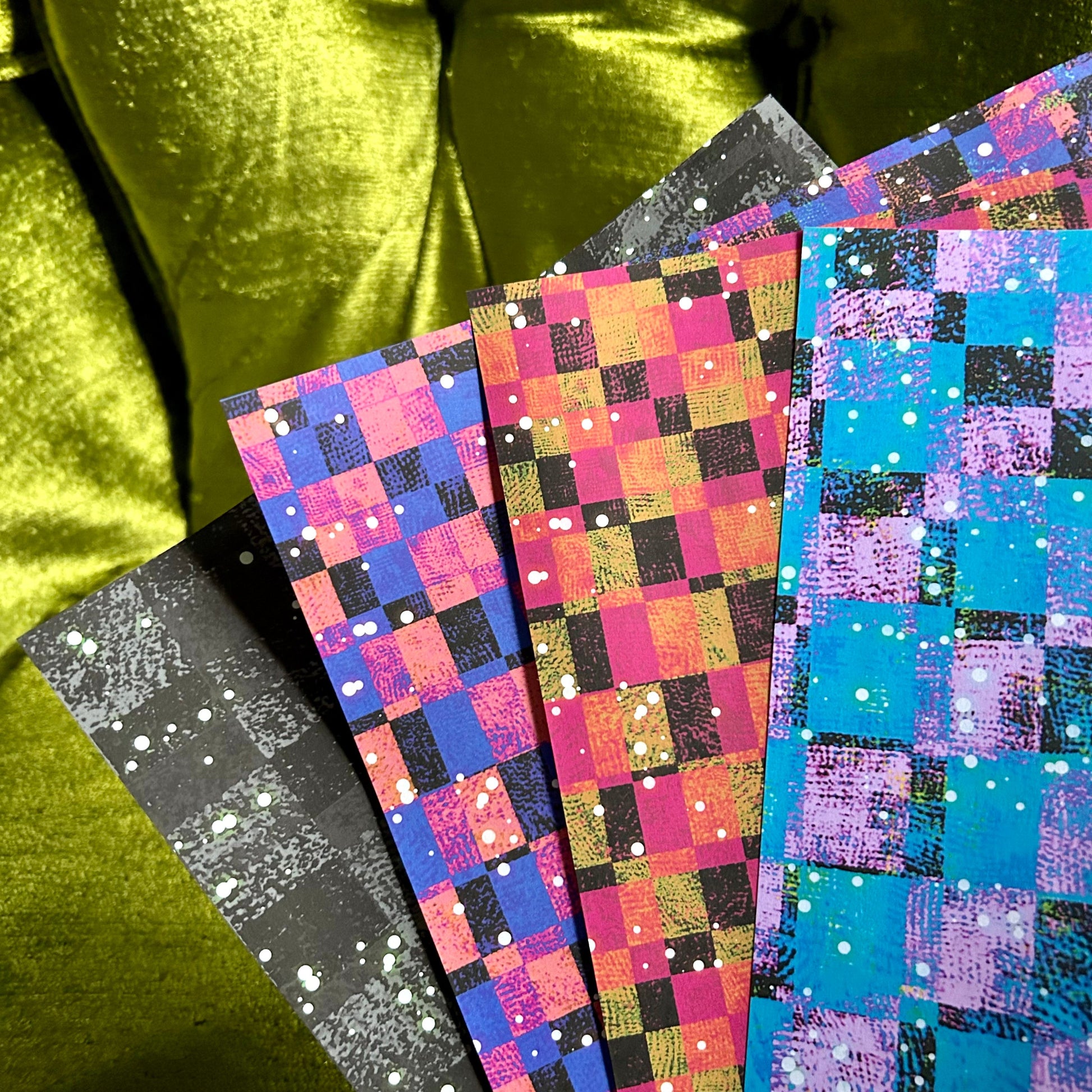 Colorful checkered paper sheets on a green fabric background