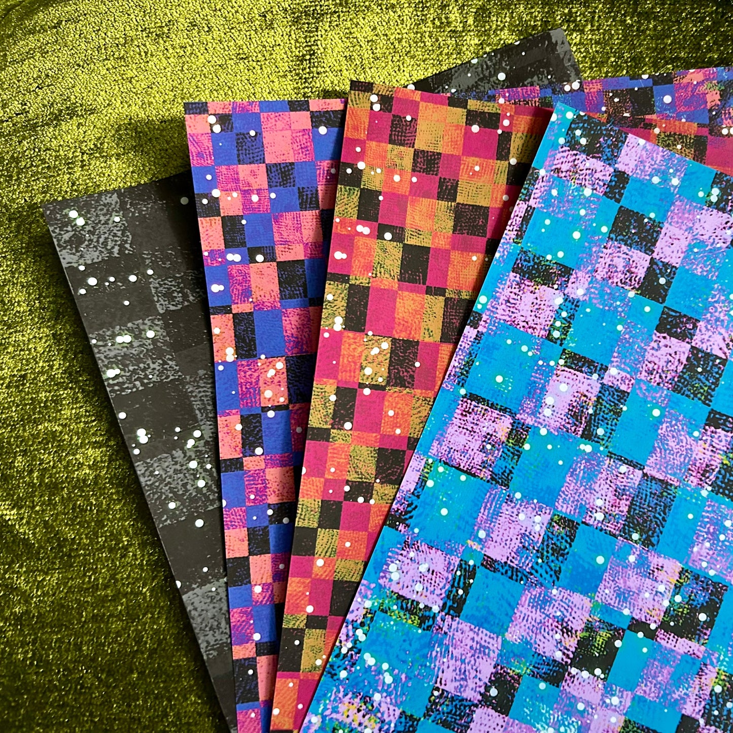 Set of colorful checkered paper sheets on a green surface