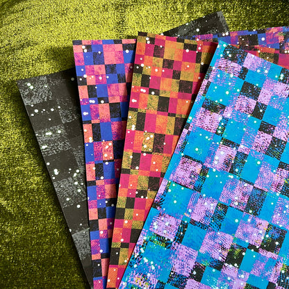 Set of colorful checkered paper sheets on a green surface