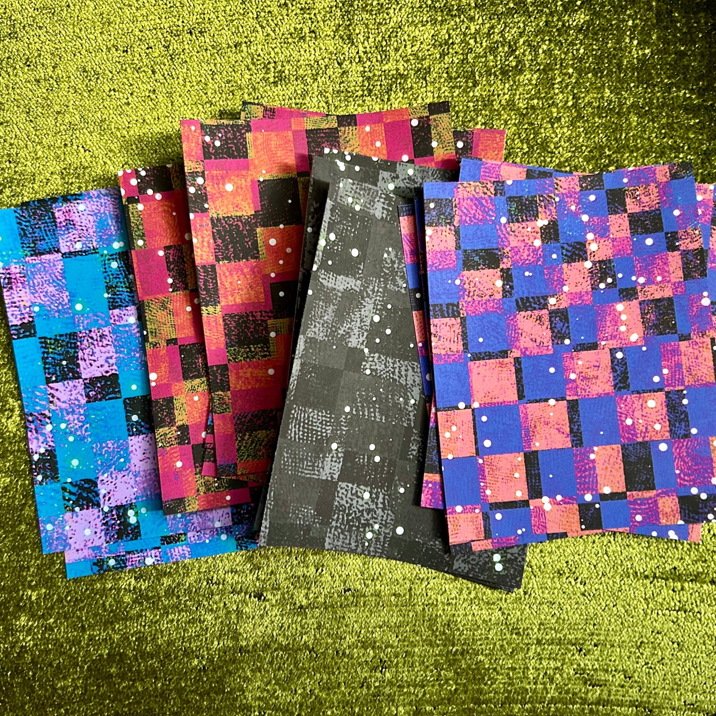 Set of colorful checkered papers on a green textured surface