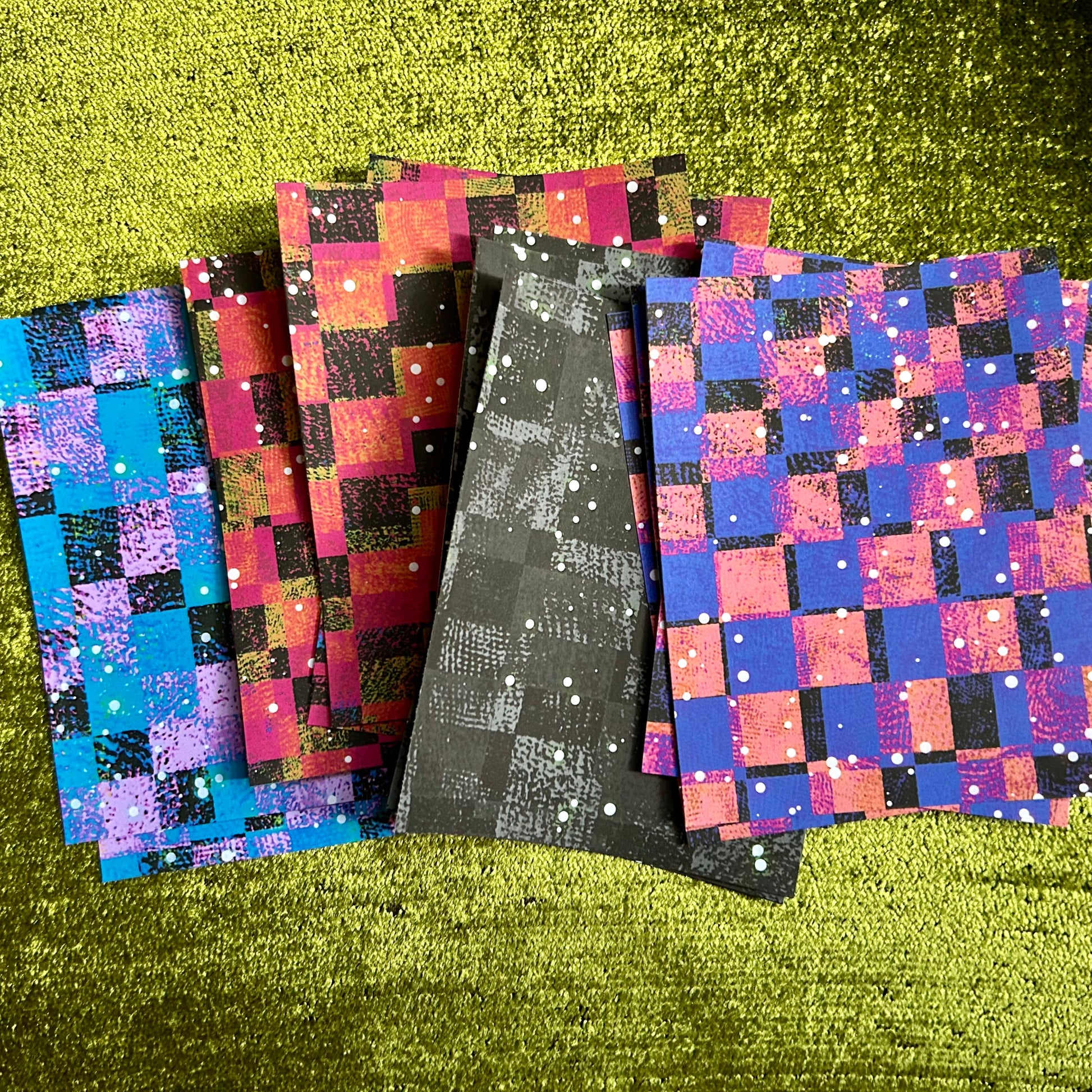 Set of colorful checkered papers on a green textured surface