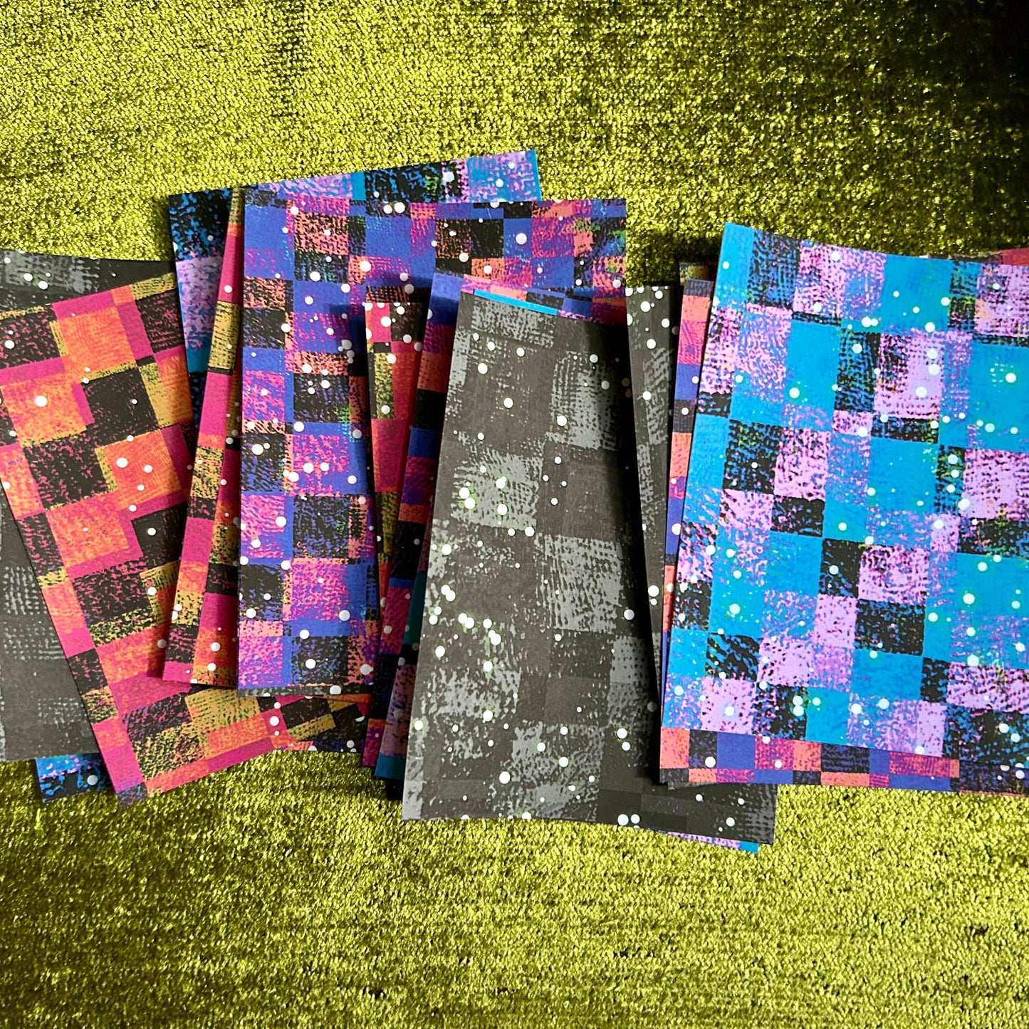 Set of colorful checkered papers on a green textured surface