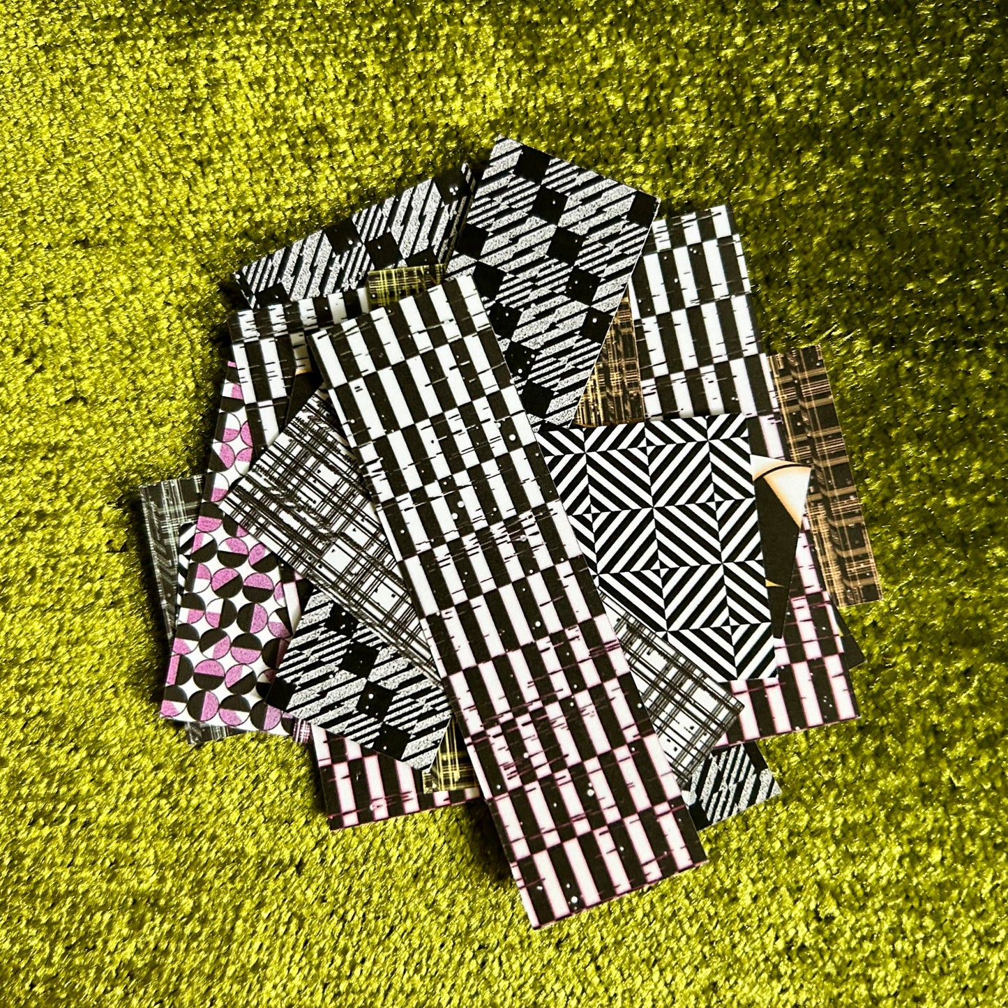 Stack of black and white patterned sticker scraps on a green textured surface
