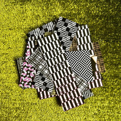Stack of black and white patterned sticker scraps on a green textured surface