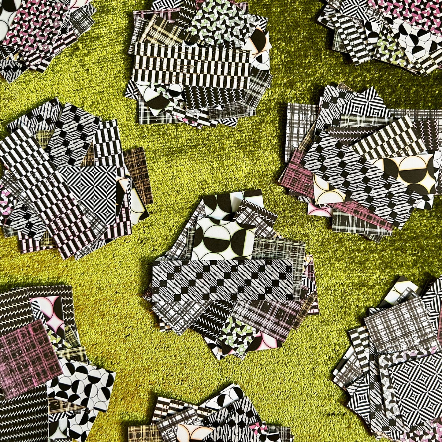 Collection of black and white patterned sticker scraps on a green background
