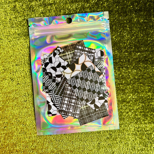 Holographic packaging with black and white patterned sticker sheets on a green textured background