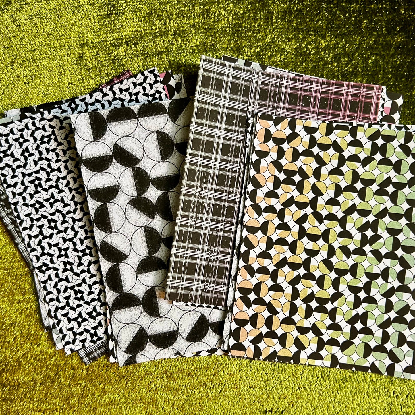 Sticker sheets with different cosmic patterns on a textured green surface