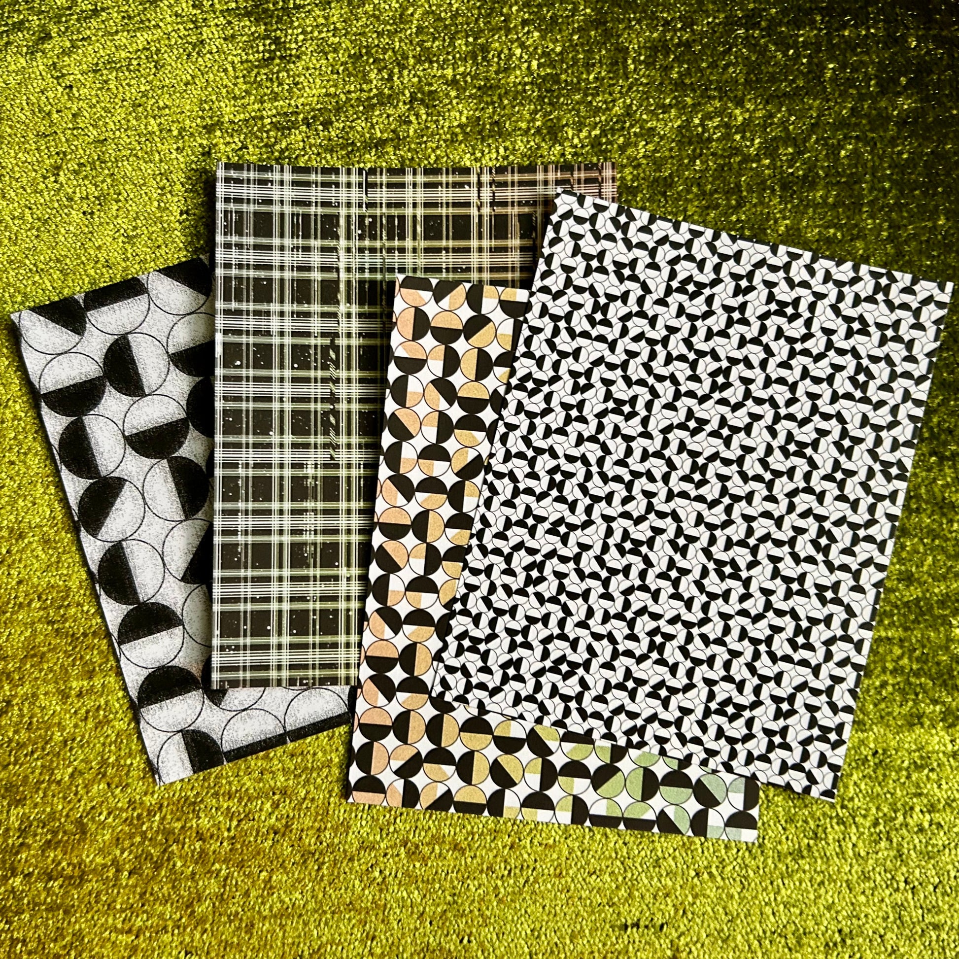Four patterned sticker sheets on a textured green surface