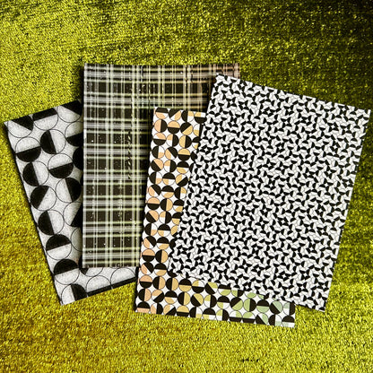 Four patterned sticker sheets on a textured green surface