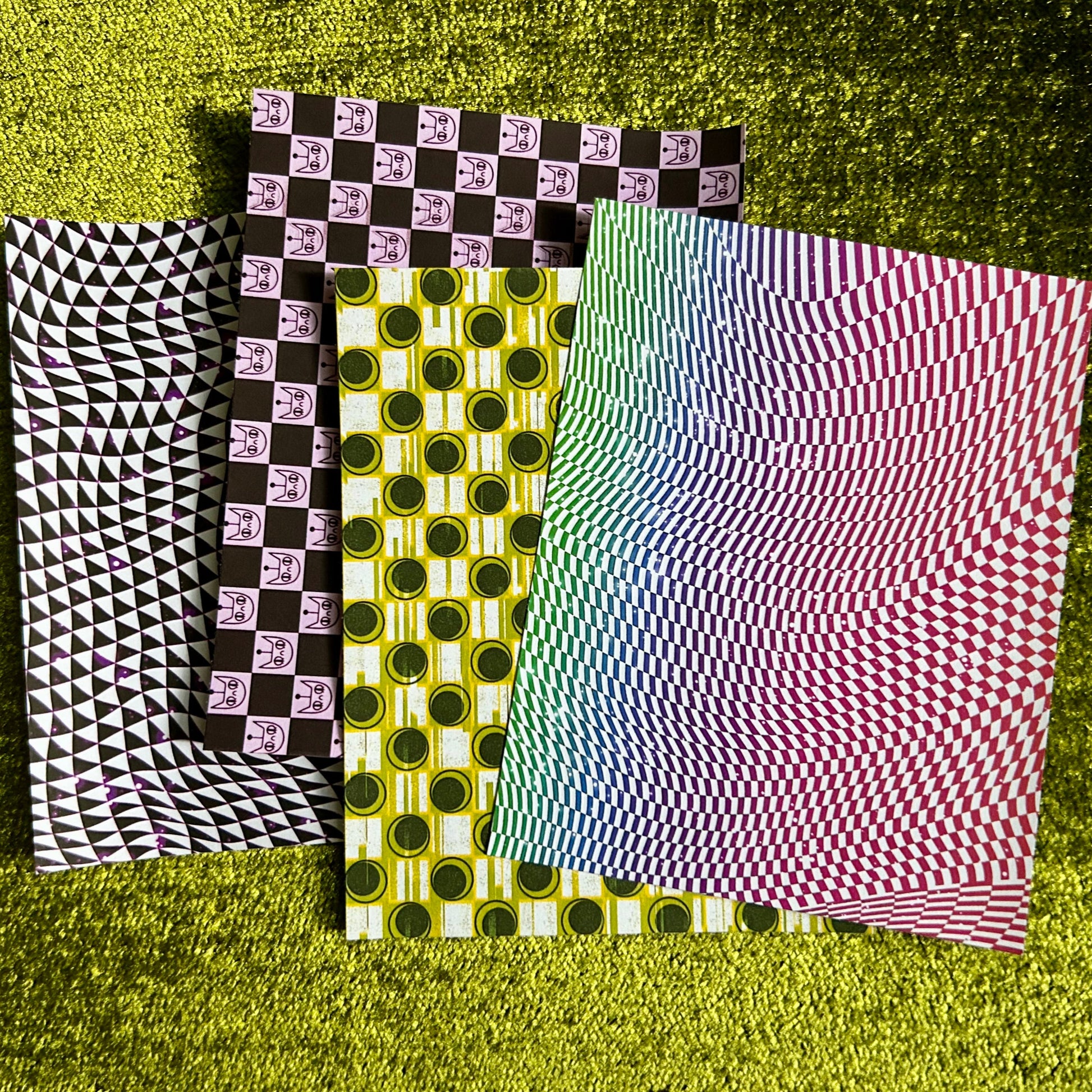 Four sheets of patterned sticker paper on a textured green surface