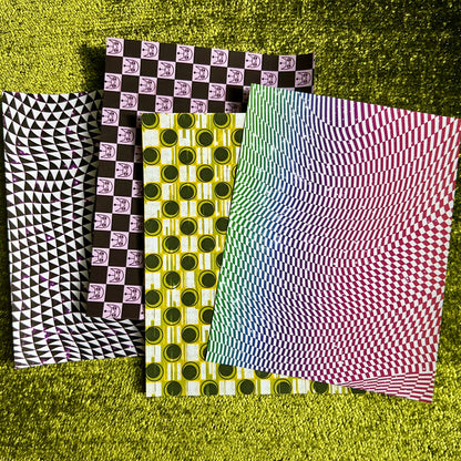 Four sheets of patterned sticker paper on a textured green surface