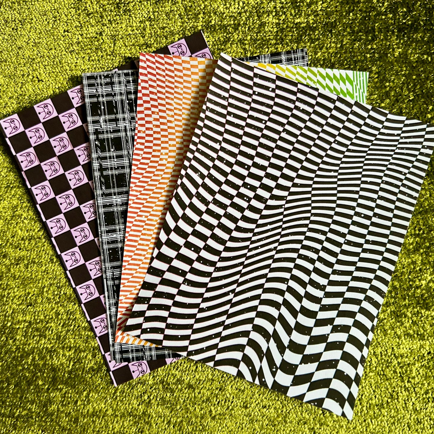 Collection of patterned sticker paper sheets on a green textured surface