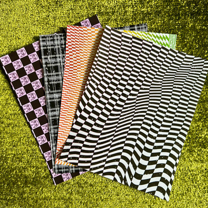 Collection of patterned sticker paper sheets on a green textured surface