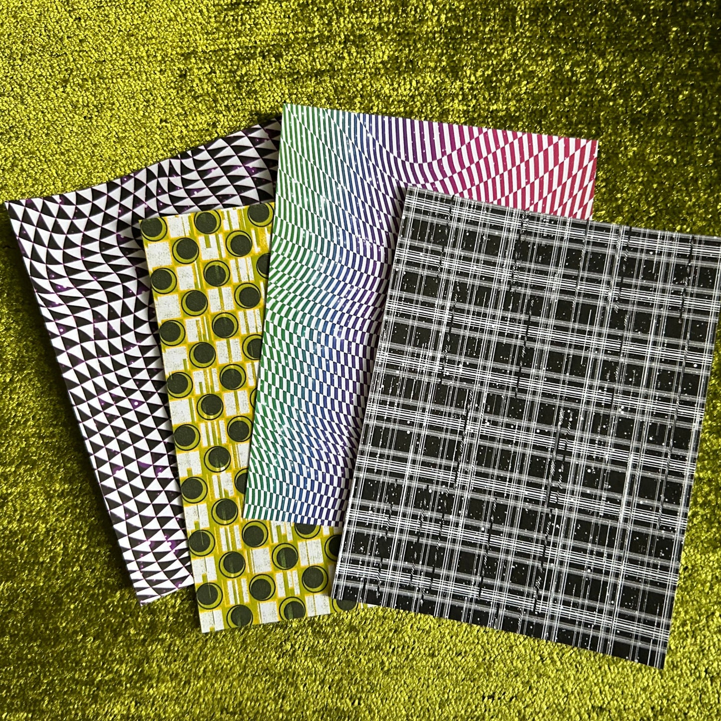 Four different patterned sticker sheets on a textured green surface