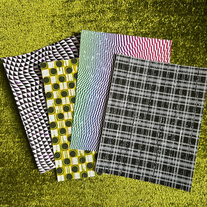 Four different patterned sticker sheets on a textured green surface
