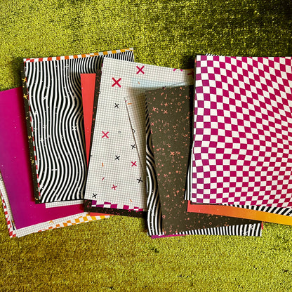Collection of patterned pieces of sticker paper on a textured green surface