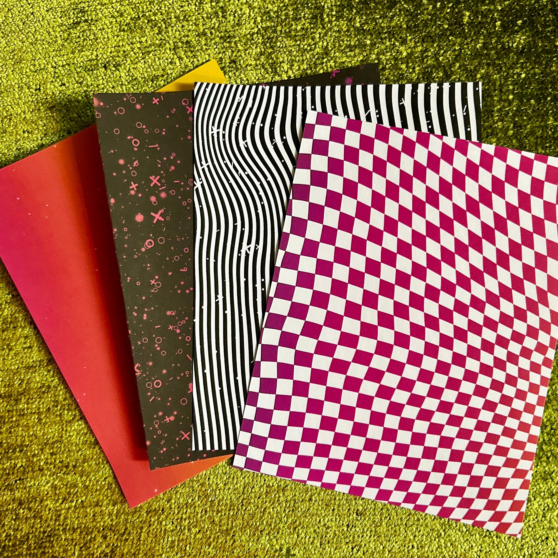 Four patterned pieces of sticker paper on a textured green surface