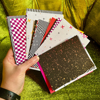 Hand holding a stack of patterned pieces of paper on a green textured surface