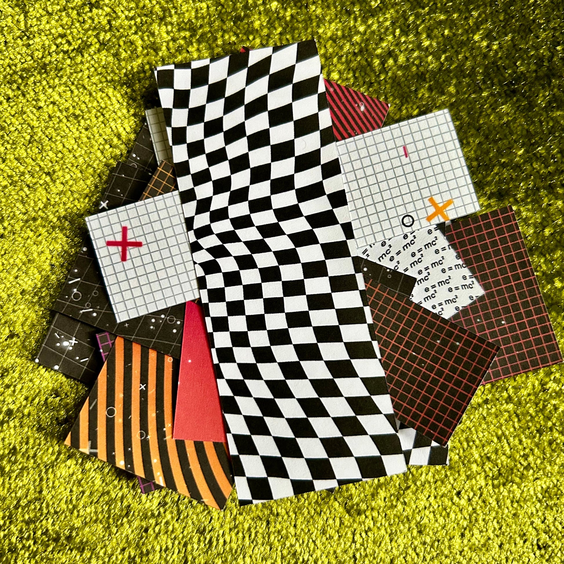 Collection of patterned paper squares on a textured green surface