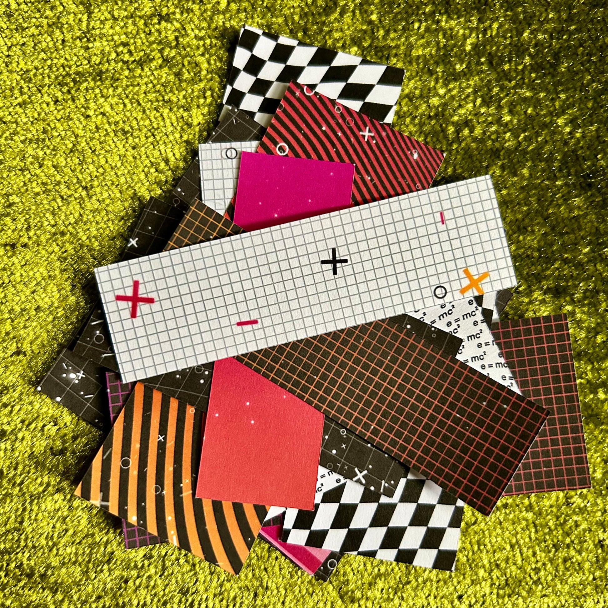 Collection of patterned paper squares on a green textured surface