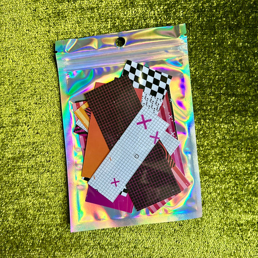Holographic pouch with colorful sticker scraps on a green textured background