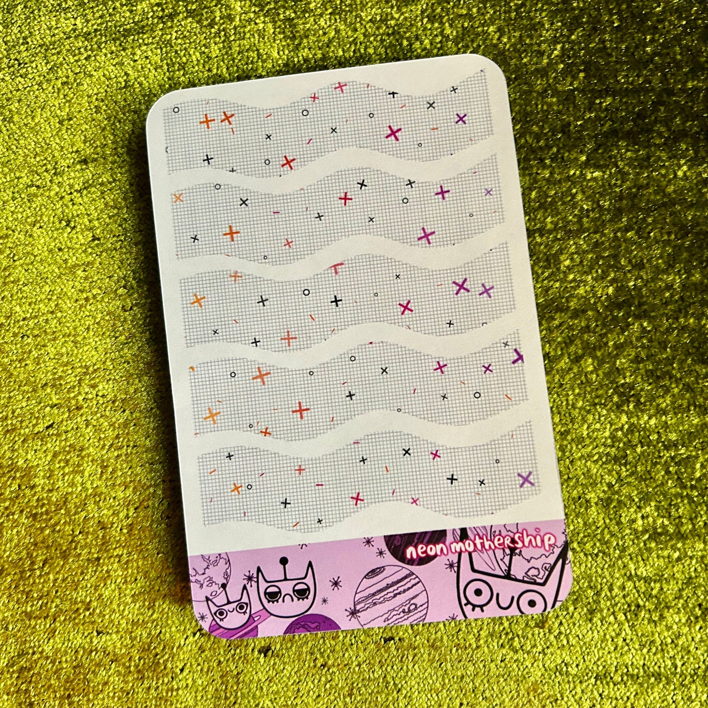 sticker sheet with patterned wavy lines on a green textured surface