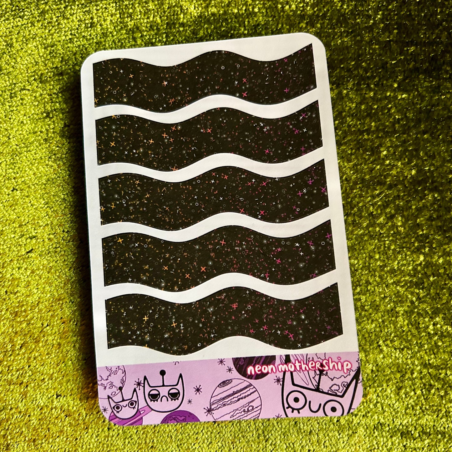 sticker sheet with wavy black pattern on a green textured surface