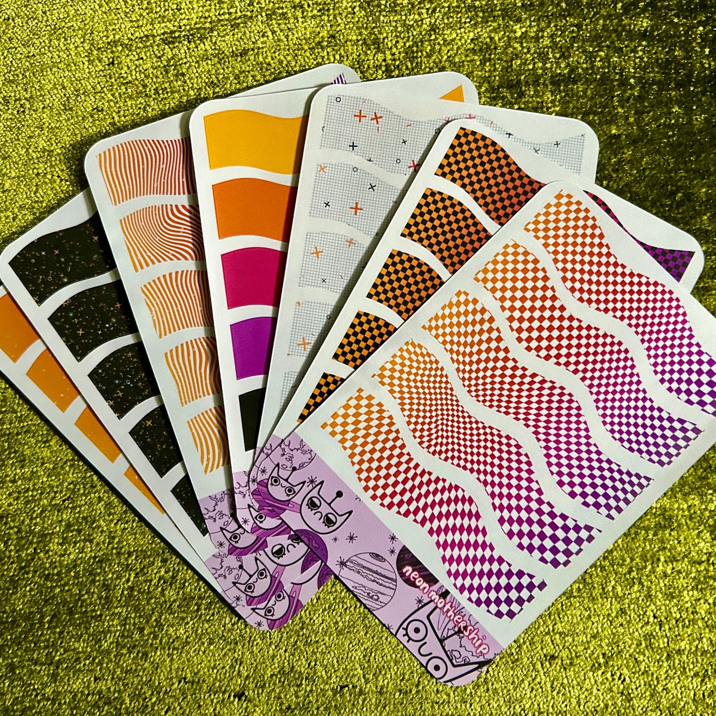 Set of patterned sticker sheets on a textured green surface