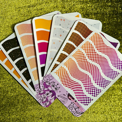 Set of patterned sticker sheets on a textured green surface