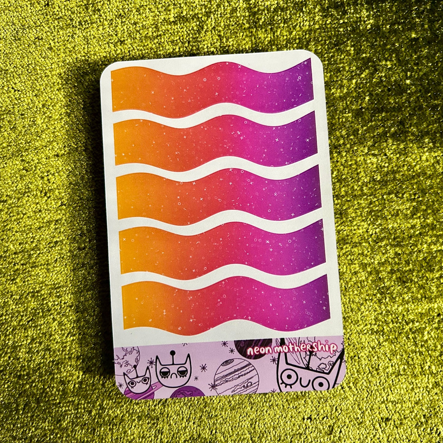 Colorful wavy-patterned sticker sheet on a green textured surface