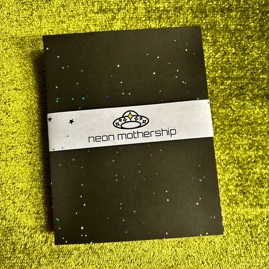 Black paper with 'neon mothership' branding on a green textured surface