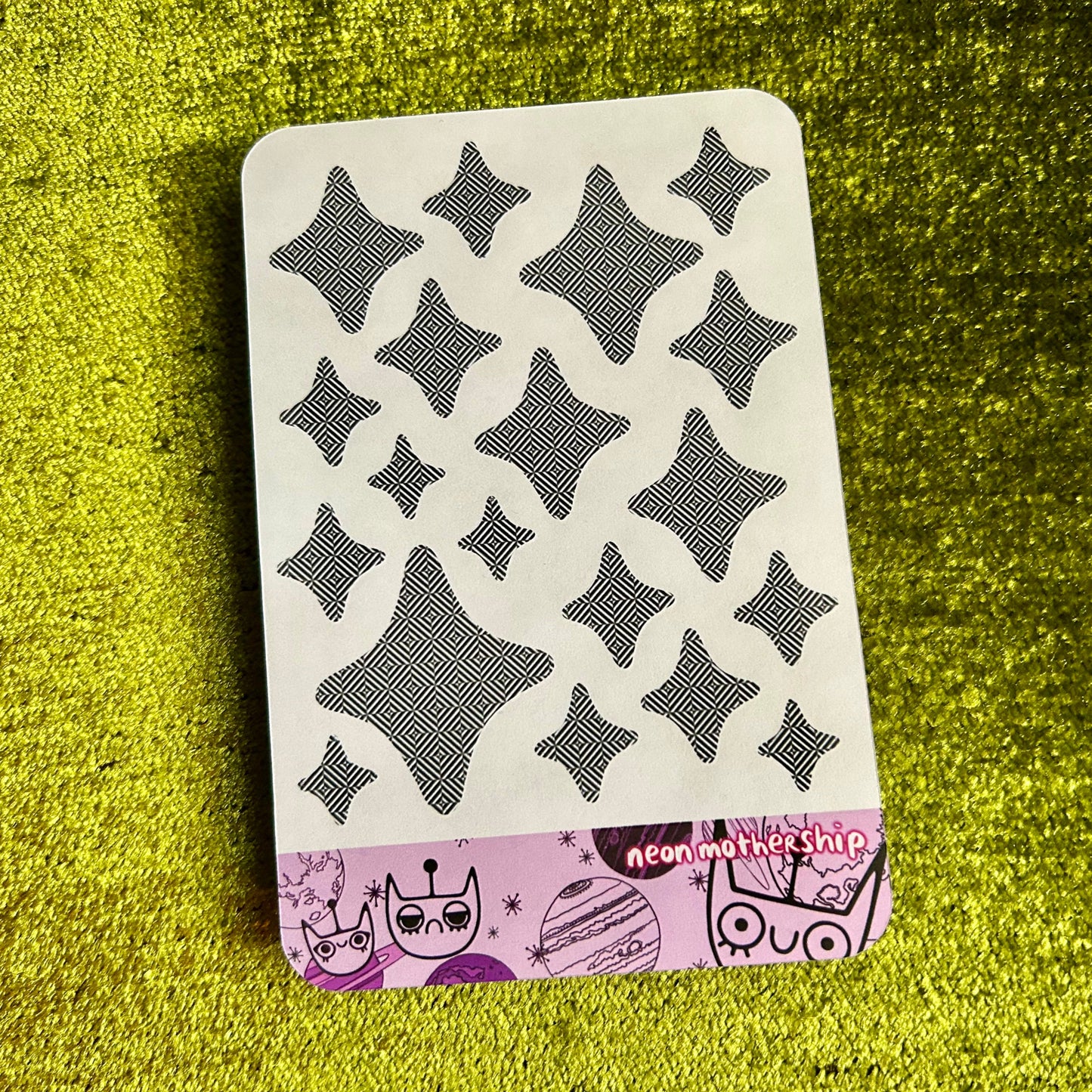 Sticker sheet with black star patterns on a green textured surface