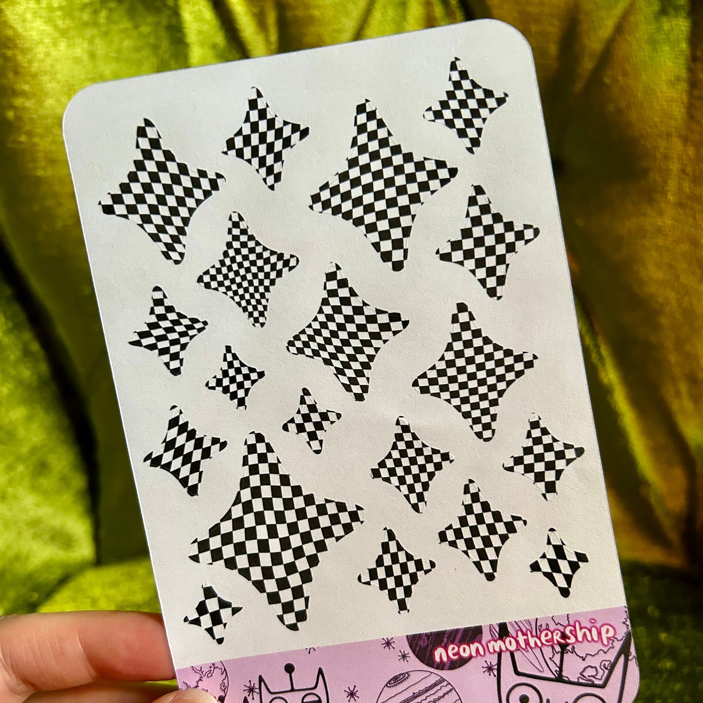 sticker sheet with black star patterns on a green fabric background
