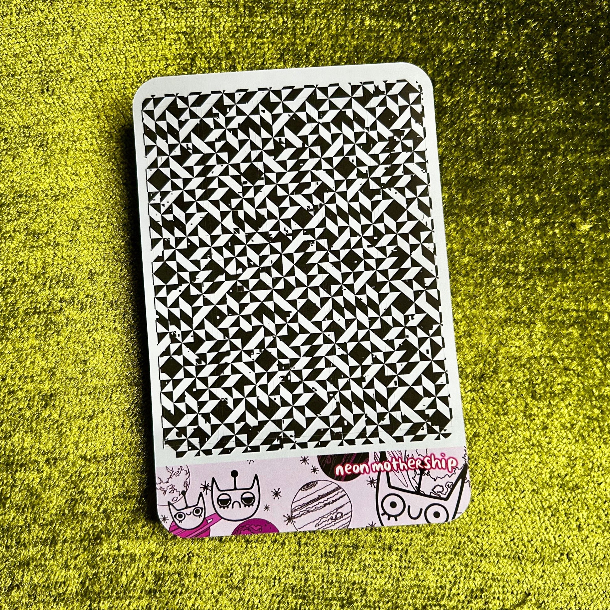 Black and white patterned sticker sheet with cartoon characters on a green textured surface