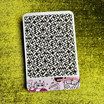 Black and white patterned sticker sheet with cartoon characters on a green textured surface