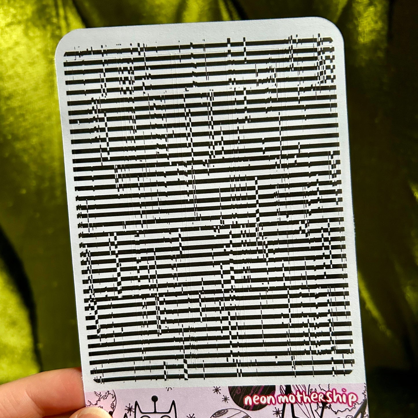 sticker sheet with black and white striped pattern held by a hand against a green background