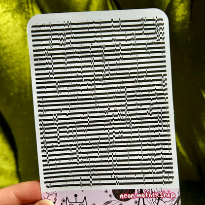 sticker sheet with black and white striped pattern held by a hand against a green background
