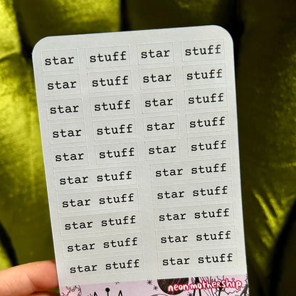 Sticker sheet with 'star stuff' text held by a hand against a green background