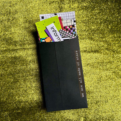 Black envelope with colorful papers on a green textured surface