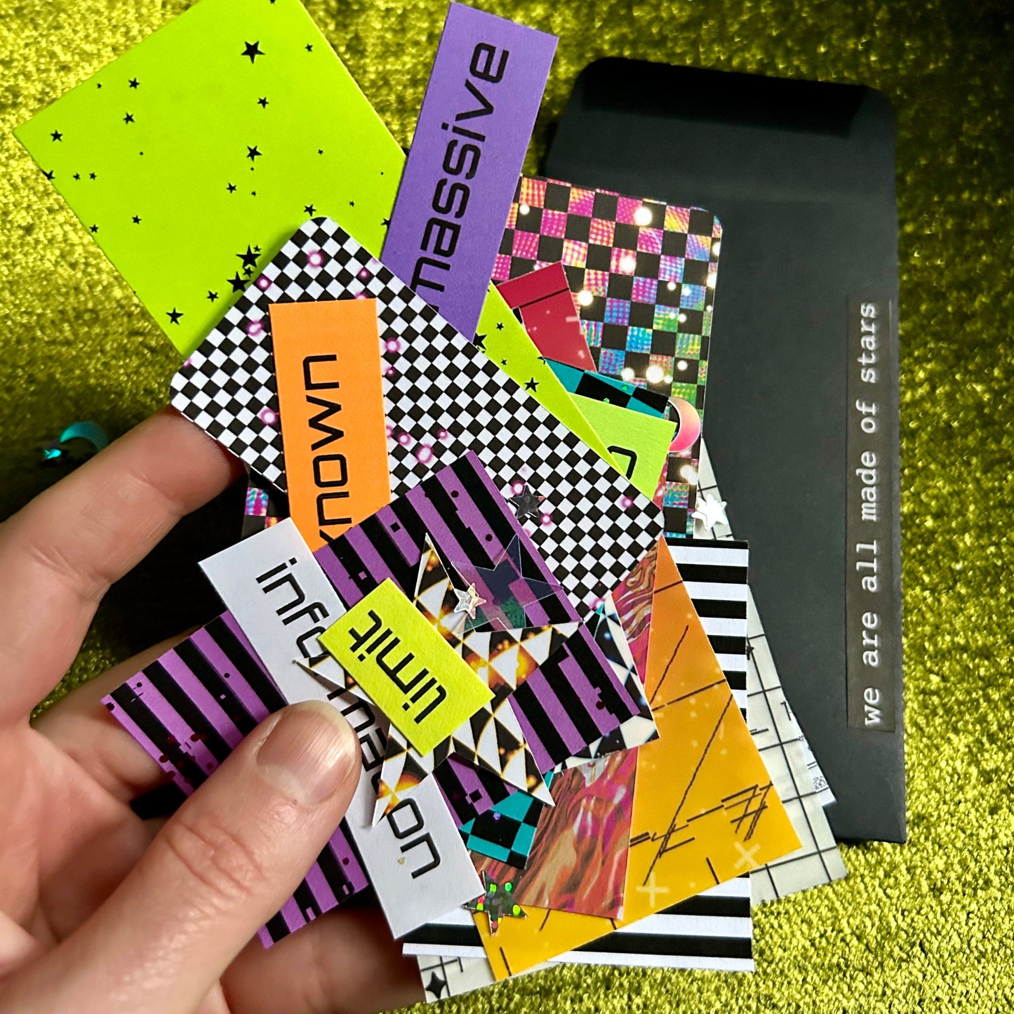 Colorful geometric papers held by a hand on a green textured background