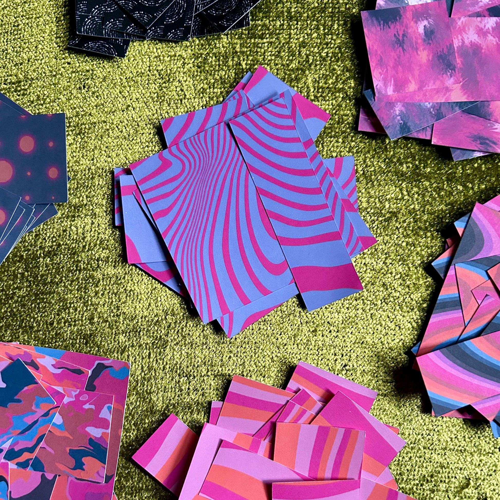 Colorful patterned paper pieces scattered on a green textured surface