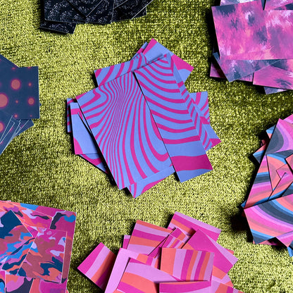 Colorful patterned paper pieces scattered on a green textured surface