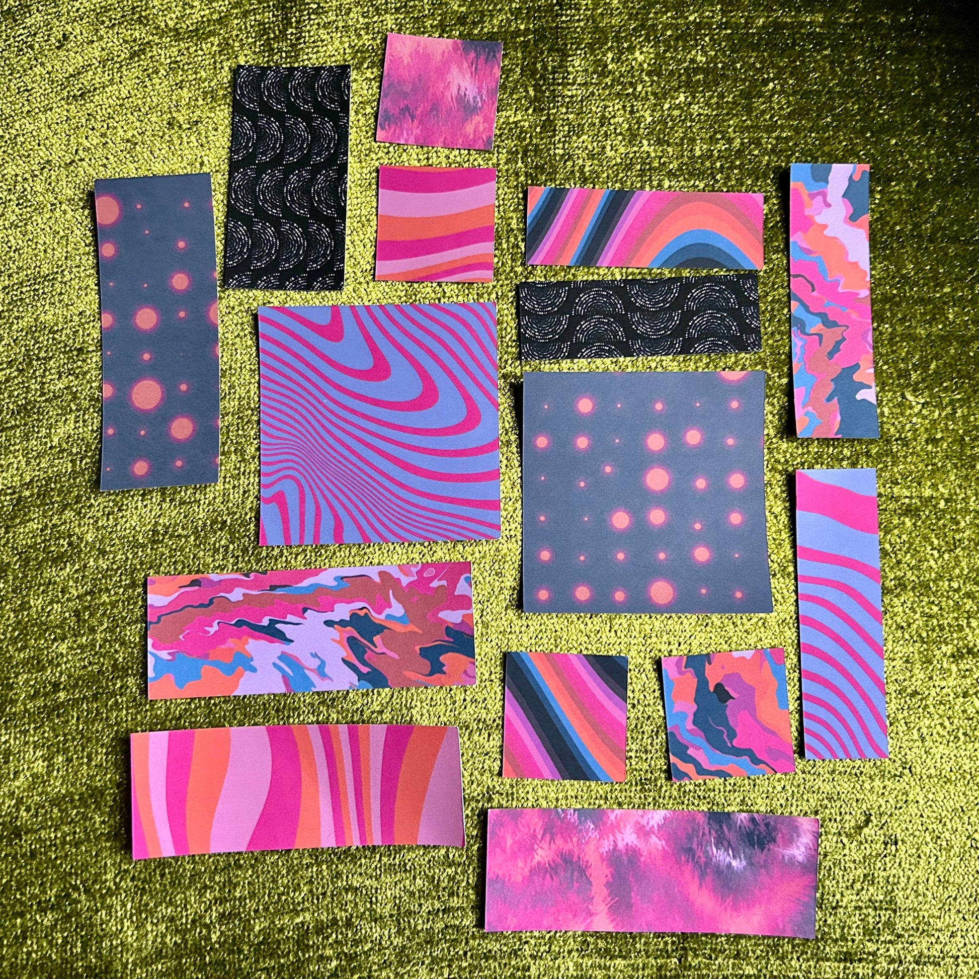 Collection of colorful patterned sticker papers on a green textured surface