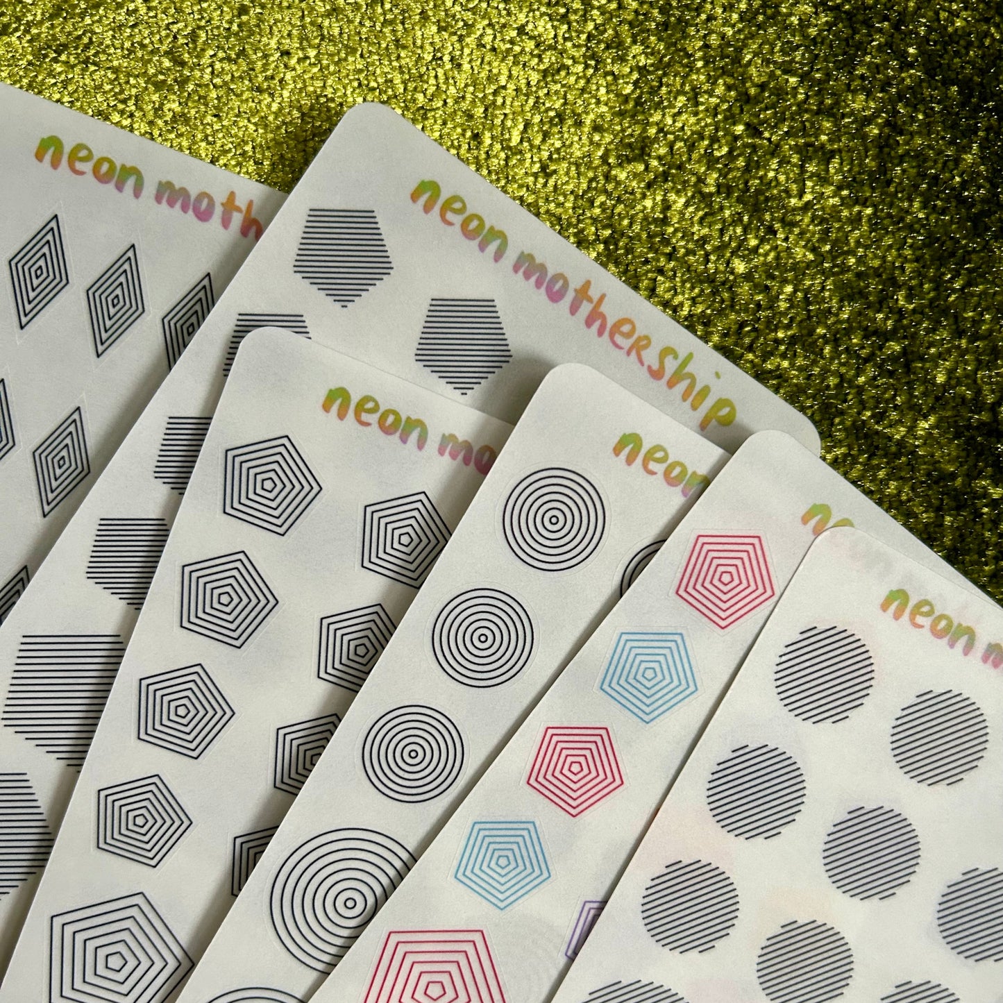 Set of neon motherShips stickers with geometric patterns on a glittery green background