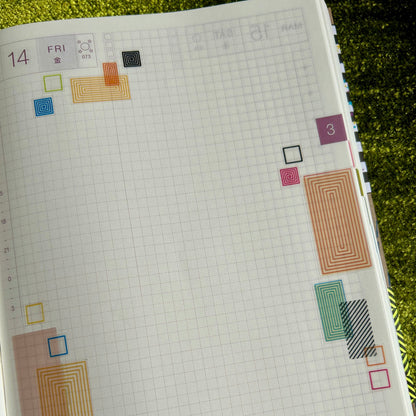 Planner page with colorful geometric shapes on a green surface