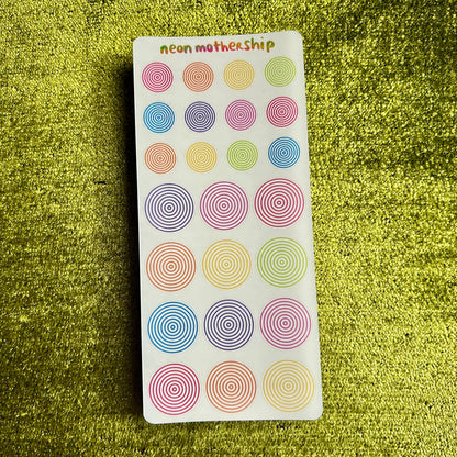 Pack of colorful circular stickers on a green textured surface