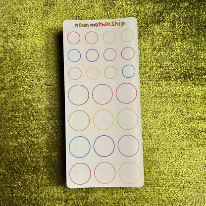 Sheet of circular stickers with colored borders on a green textured background