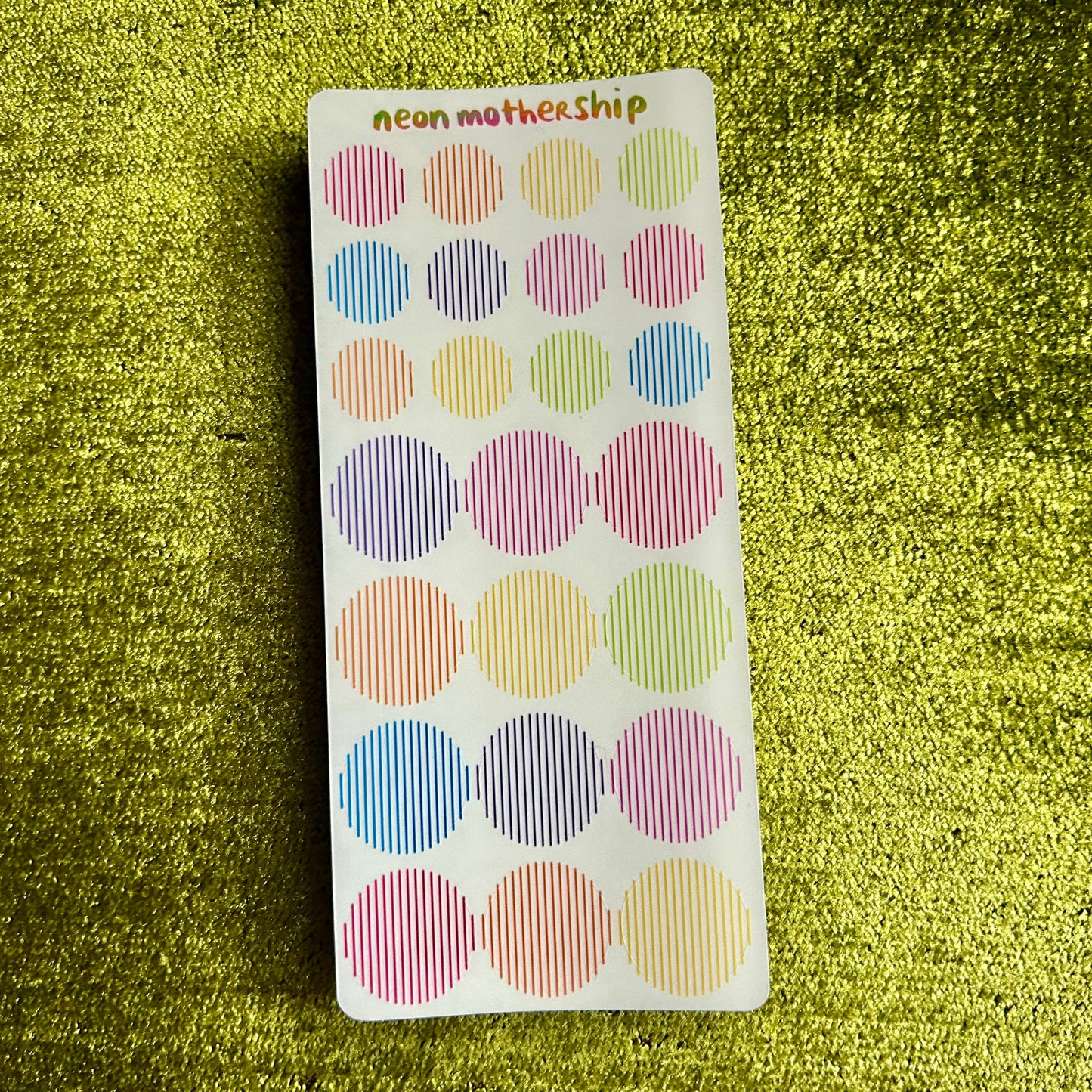 Pack of colorful dot stickers on a green textured background